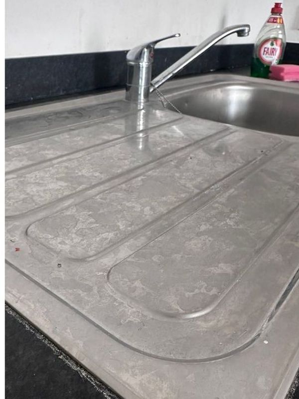Before: the kitchen sink and draining board dulled by limescale